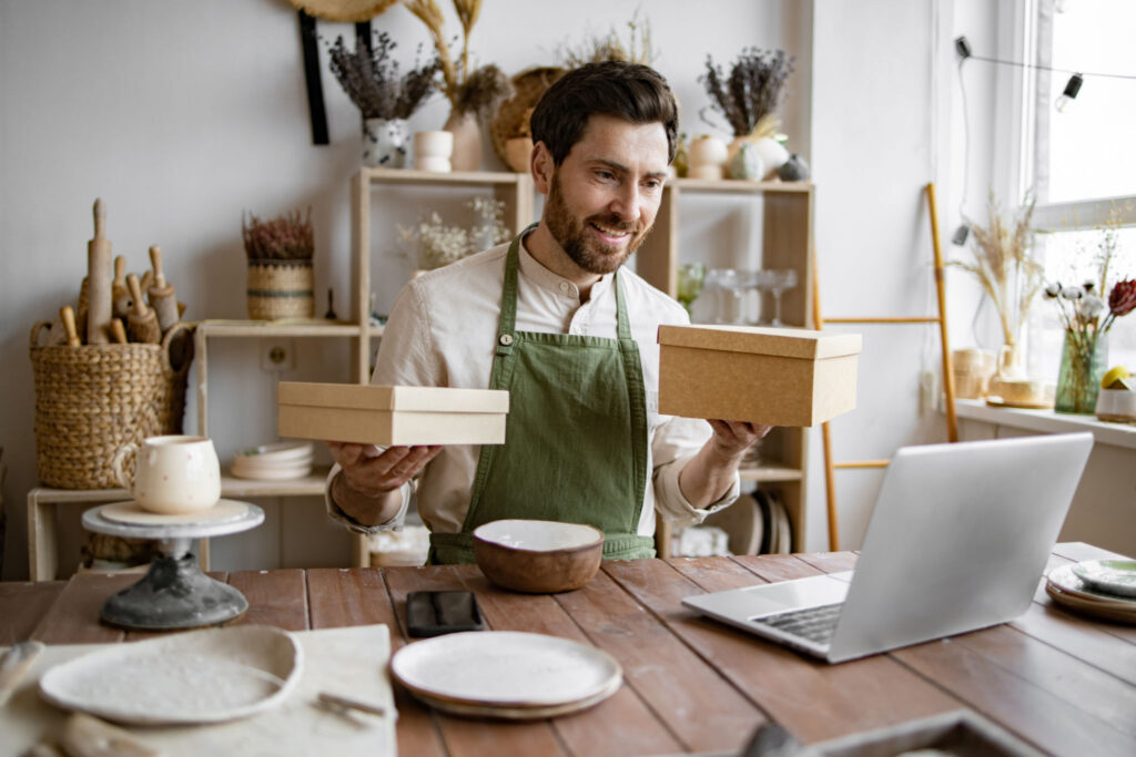 E-commerce entrepreneurship. Male online store preparing an order for shipping in a warehouse. Small business owner packing his handmade product into cardboard box.